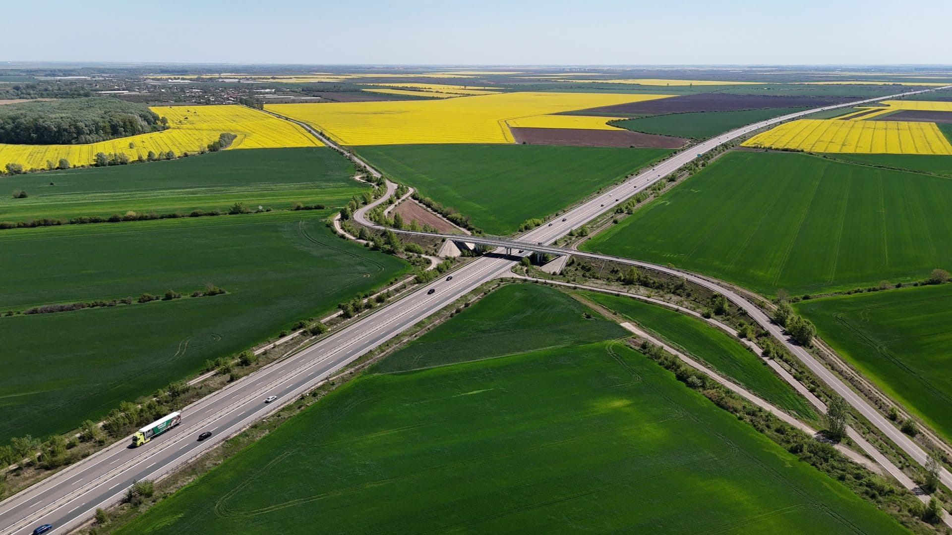 Snelweg met een knooppunt door groene velden, van bovenaf gezien